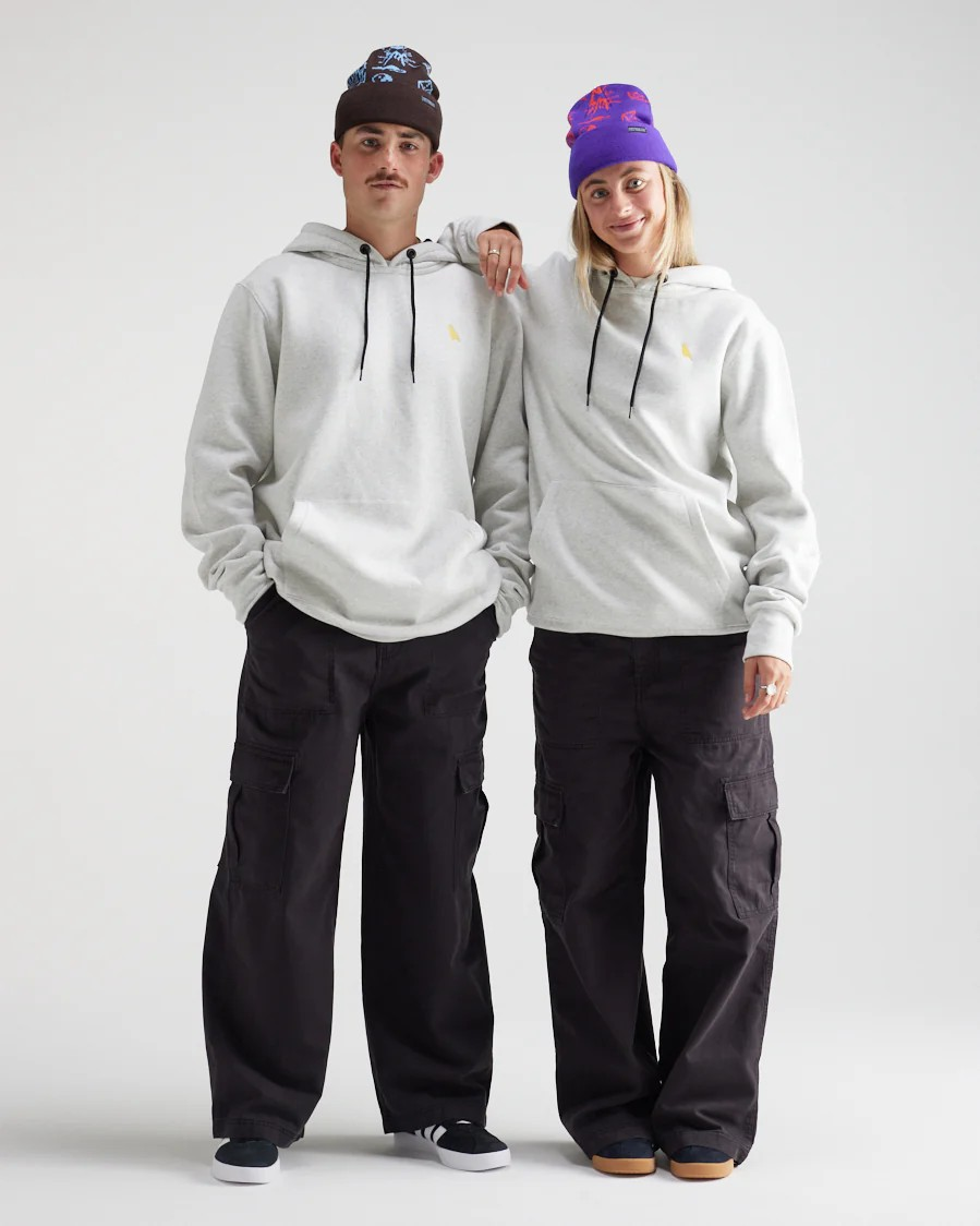 Two people wearing matching gray hoodies and black pants on a white background